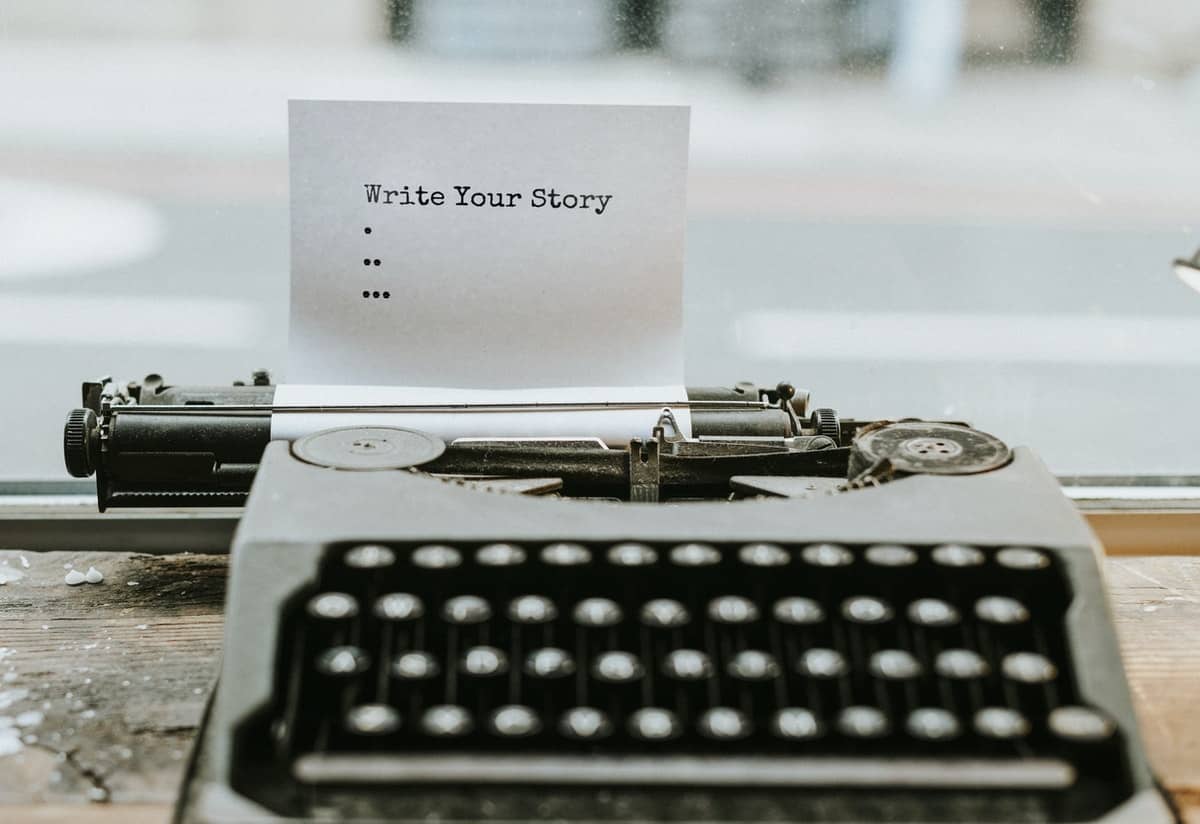 A typewriter sits on a desk with a piece of paper in it that reads 'write your story'.