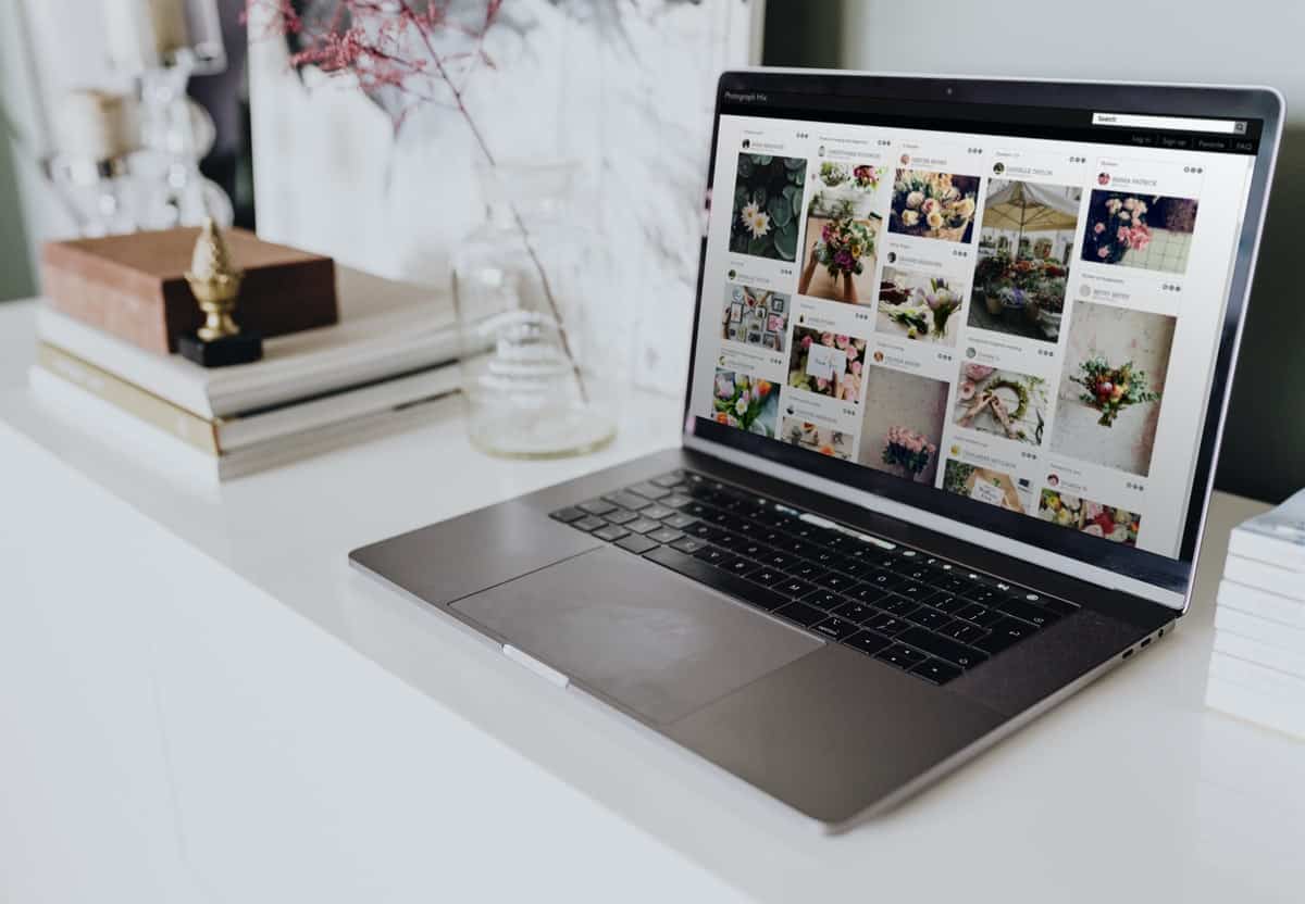 Stock website images of flowers on the screen of a laptop sitting on a white desk.